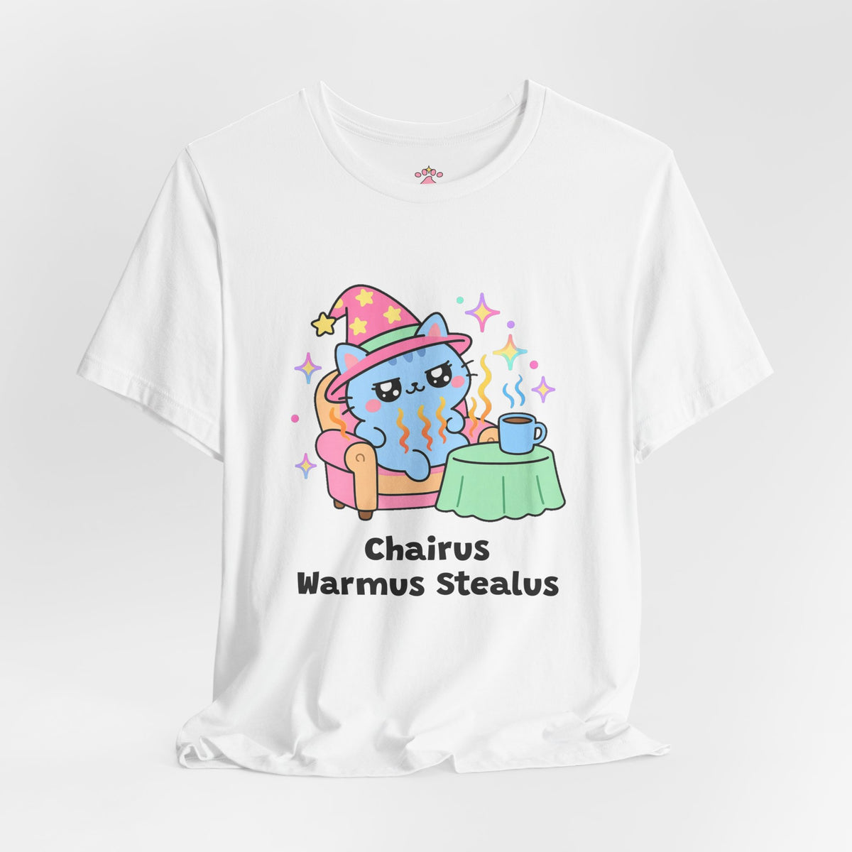 White Chairus Warmus Stealus wizard cat T-shirt shown in a soft studio setting: blue wizard cat in a pink hat lounging in a warm orange armchair beside a coffee mug