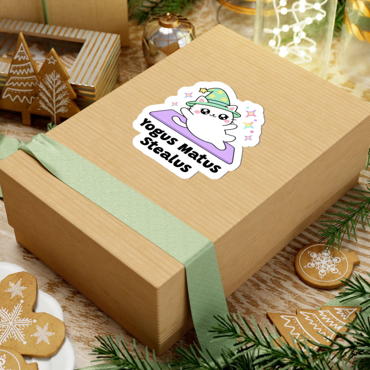 Yogus Matus Stealus wizard cat sticker on a kraft gift box with a green ribbon and holiday cookies
