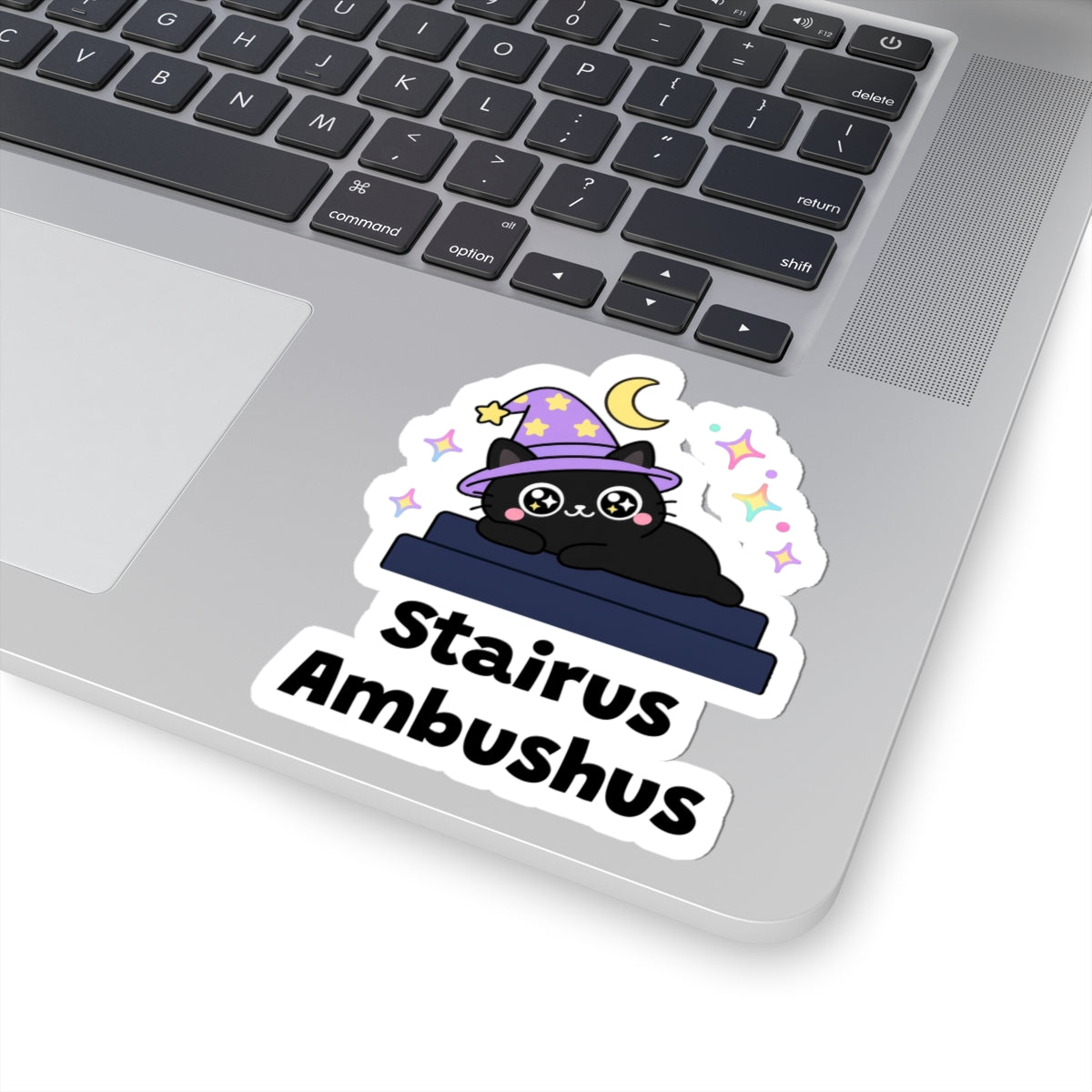 Stairus Ambushus wizard cat sticker stuck on a silver laptop next to the keyboard