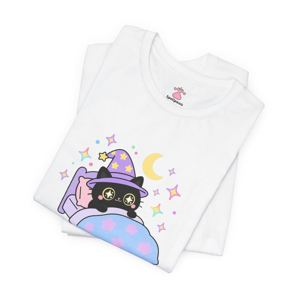 Folded white Stareus Darknus T-shirt showing a close-up of the black wizard cat in a purple hat with glowing star eyes peeking over a blue blanket under a crescent moon