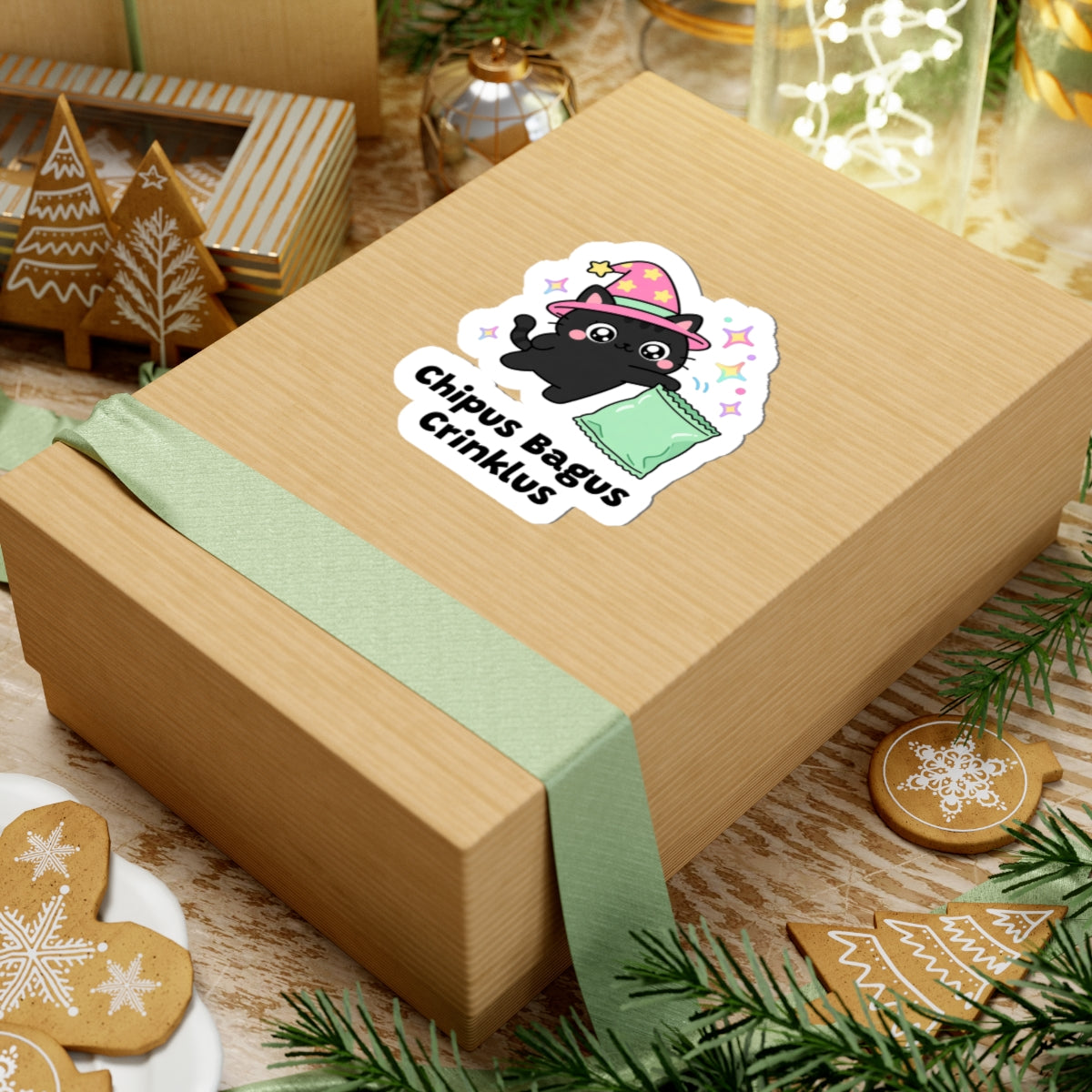 Chipus Bagus Crinklus wizard cat sticker on a kraft gift box with a green ribbon and holiday cookies