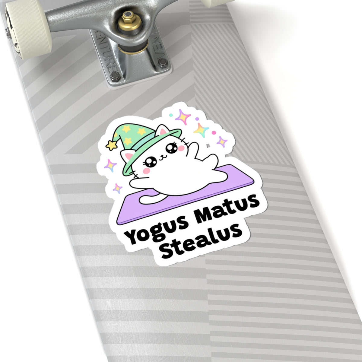 Yogus Matus Stealus wizard cat sticker on a grey skateboard deck near the truck
