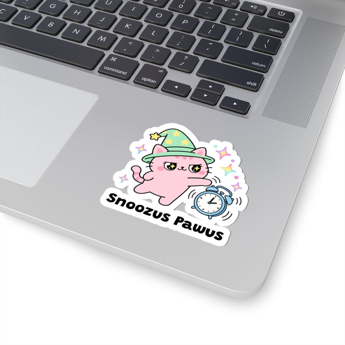Snoozus Pawus wizard cat sticker stuck on a silver laptop next to the keyboard