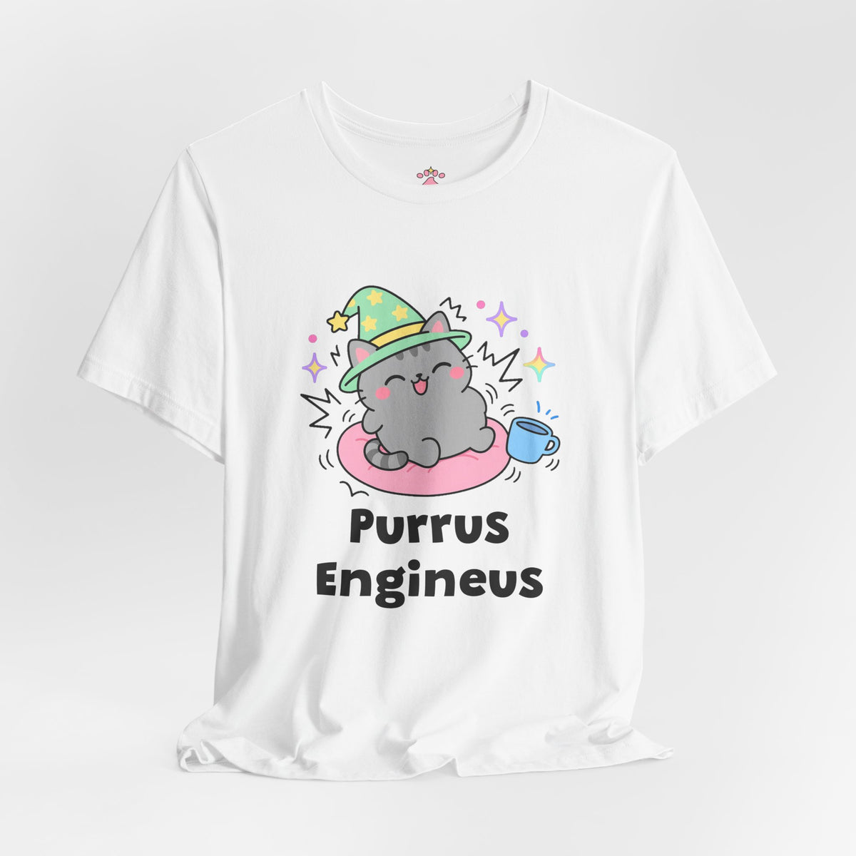 White Purrus Engineus wizard cat T-shirt shown in a soft studio setting: grey tabby wizard cat in a green hat purring loudly on a pink cushion beside a mug