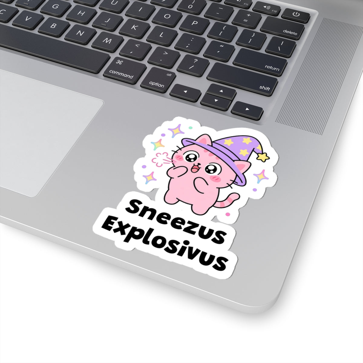 Sneezus Explosivus wizard cat sticker stuck on a silver laptop next to the keyboard