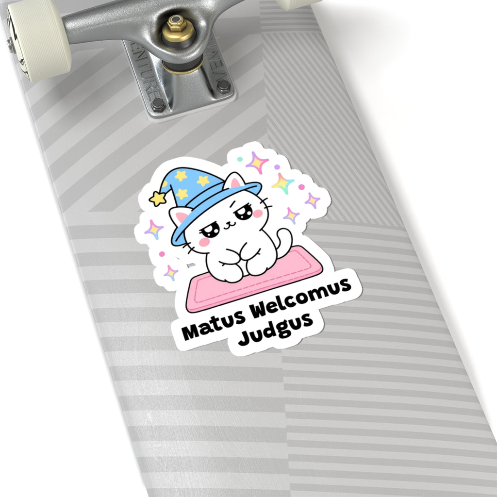 Matus Welcomus Judgus wizard cat sticker on a grey skateboard deck near the truck