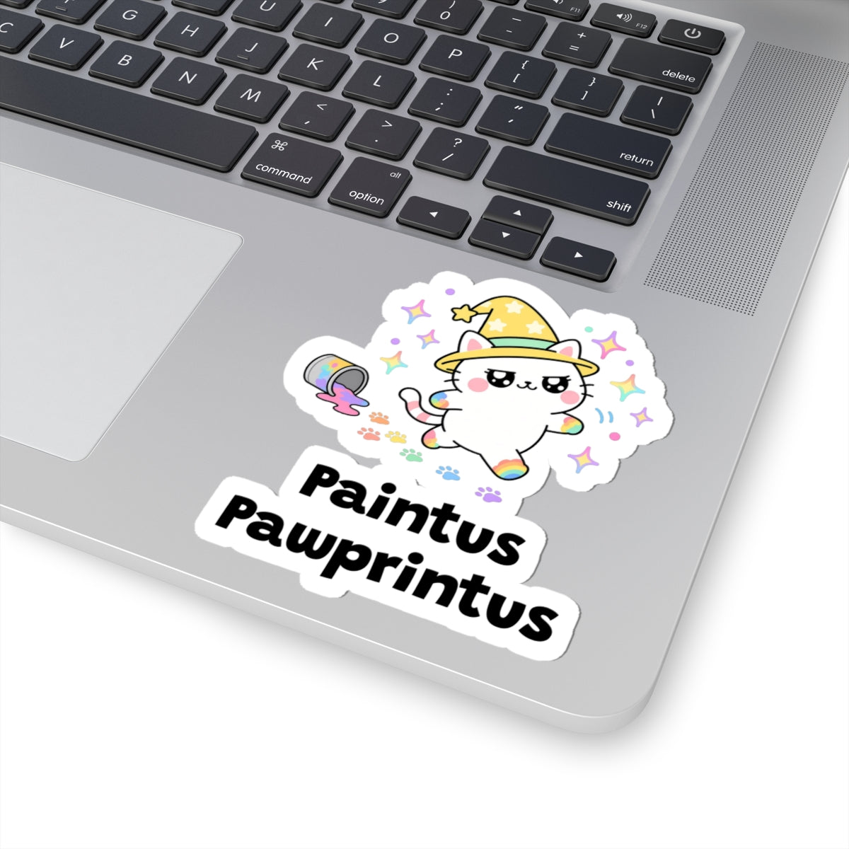 Paintus Pawprintus wizard cat sticker stuck on a silver laptop next to the keyboard