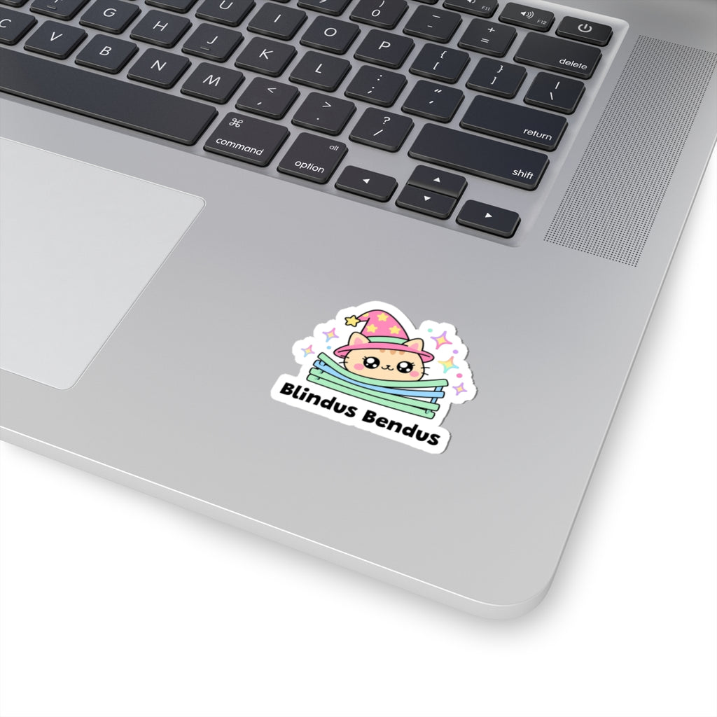 Blindus Bendus wizard cat sticker stuck on a silver laptop next to the keyboard
