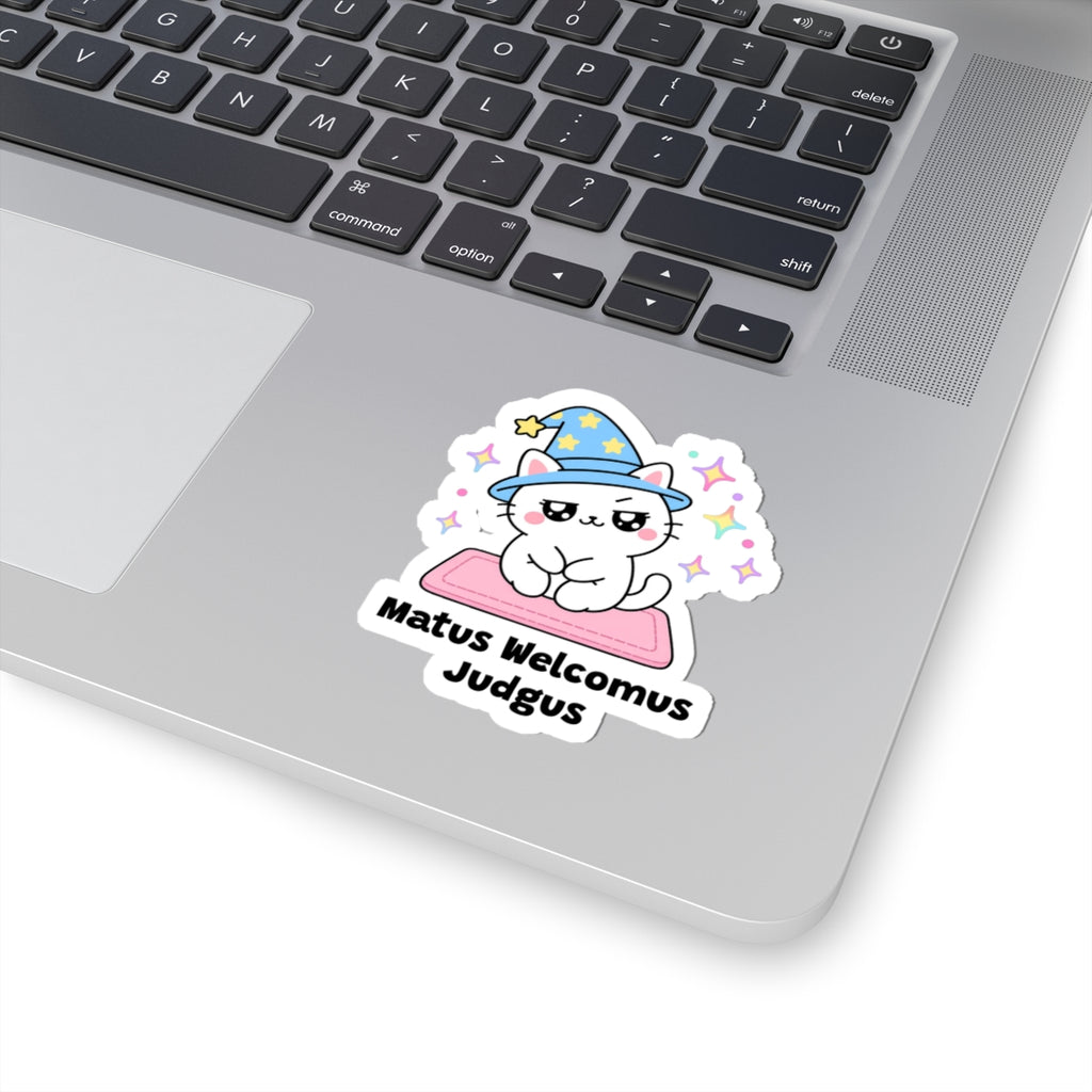 Matus Welcomus Judgus wizard cat sticker stuck on a silver laptop next to the keyboard
