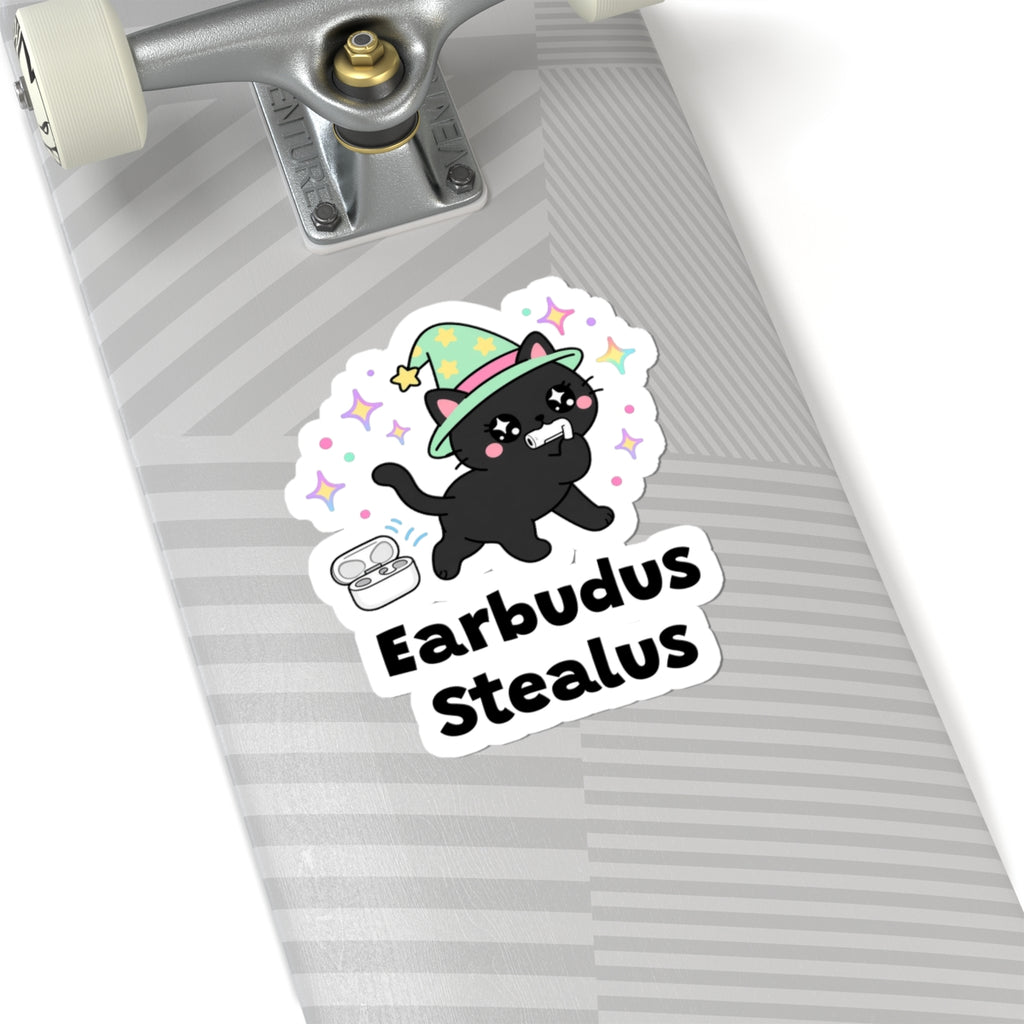 Earbudus Stealus wizard cat sticker on a grey skateboard deck near the truck