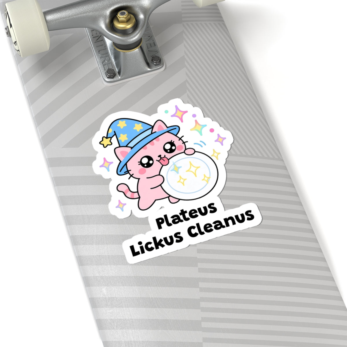 Plateus Lickus Cleanus wizard cat sticker on a grey skateboard deck near the truck