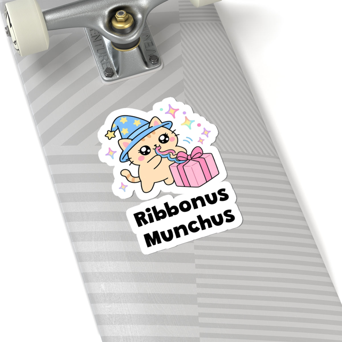 Ribbonus Munchus wizard cat sticker on a grey skateboard deck near the truck