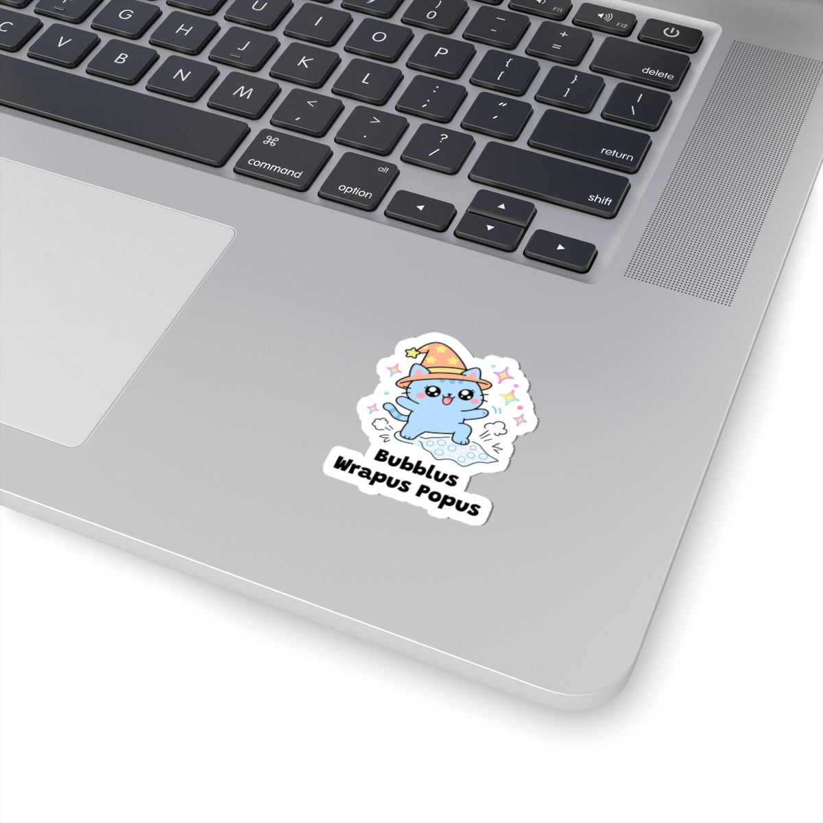 Bubblus Wrapus Popus wizard cat sticker stuck on a silver laptop next to the keyboard