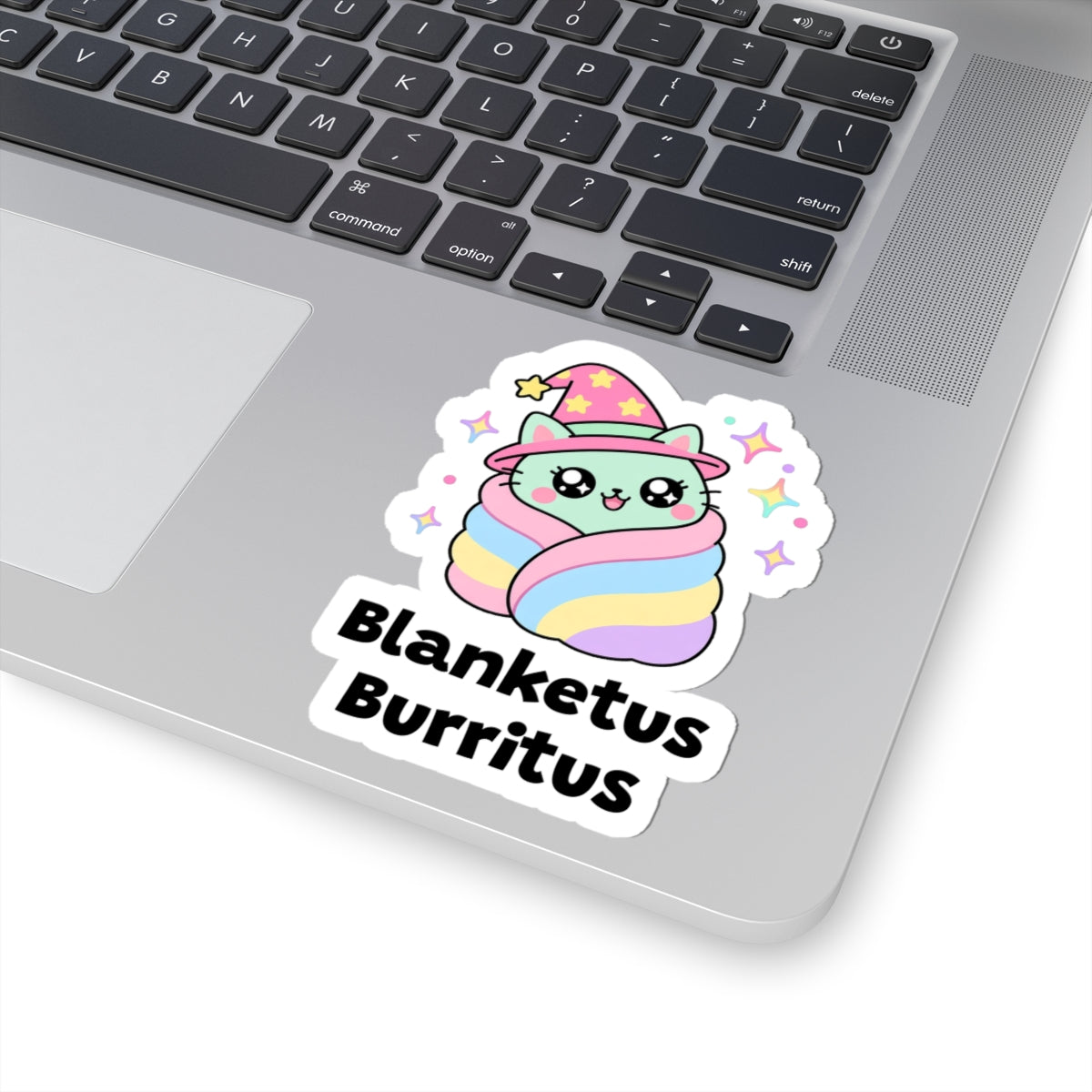 Blanketus Burritus wizard cat sticker stuck on a silver laptop next to the keyboard
