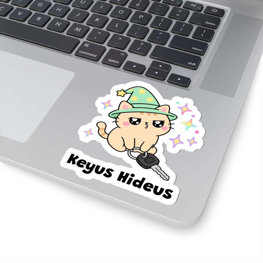 Keyus Hideus wizard cat sticker stuck on a silver laptop next to the keyboard