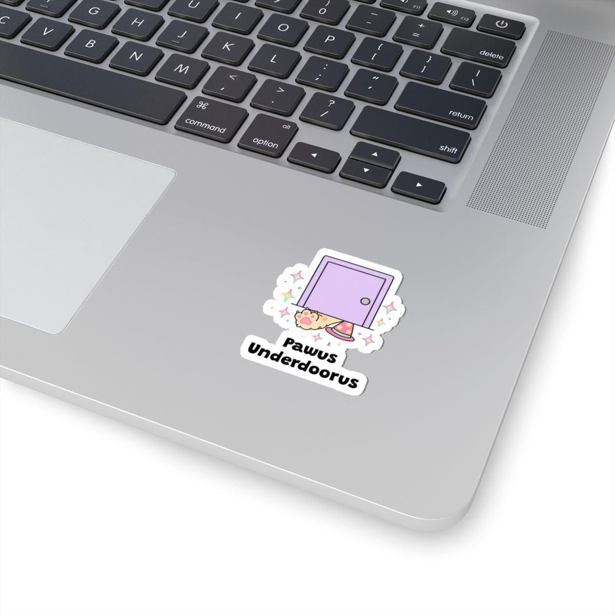Pawus Underdoorus wizard cat sticker stuck on a silver laptop next to the keyboard