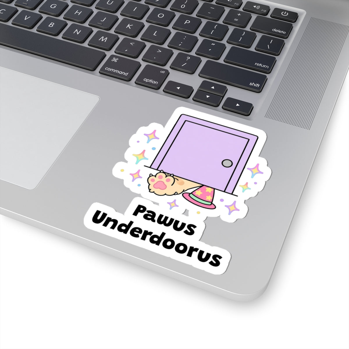 Pawus Underdoorus wizard cat sticker stuck on a silver laptop next to the keyboard