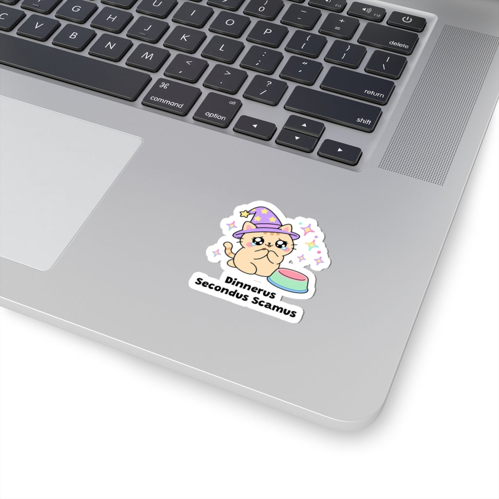 Dinnerus Secondus Scamus wizard cat sticker stuck on a silver laptop next to the keyboard