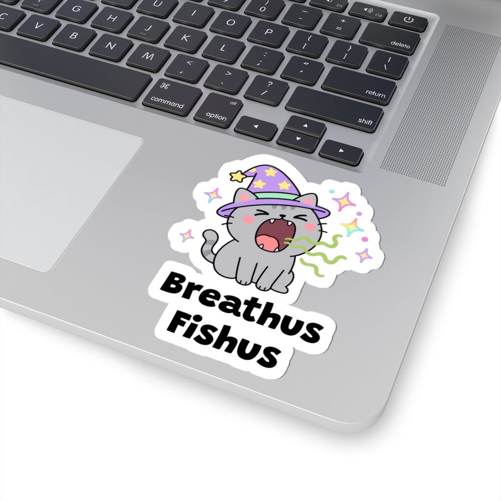 Breathus Fishus wizard cat sticker stuck on a silver laptop next to the keyboard