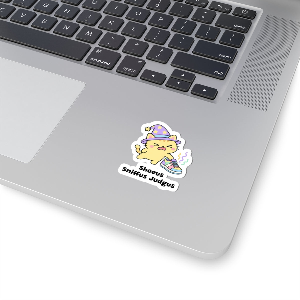 Shoeus Sniffus Judgus wizard cat sticker stuck on a silver laptop next to the keyboard