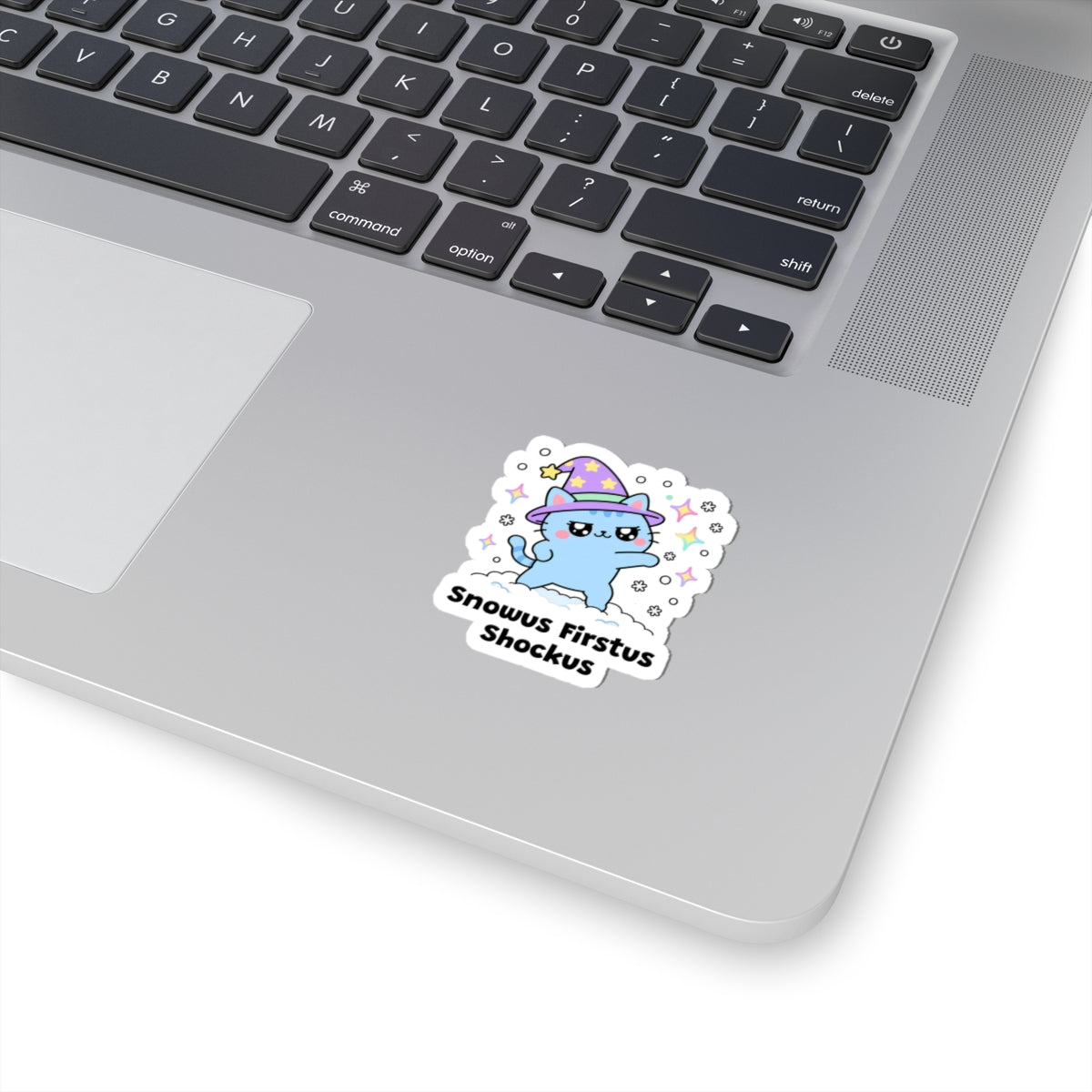 Snowus Firstus Shockus wizard cat sticker stuck on a silver laptop next to the keyboard