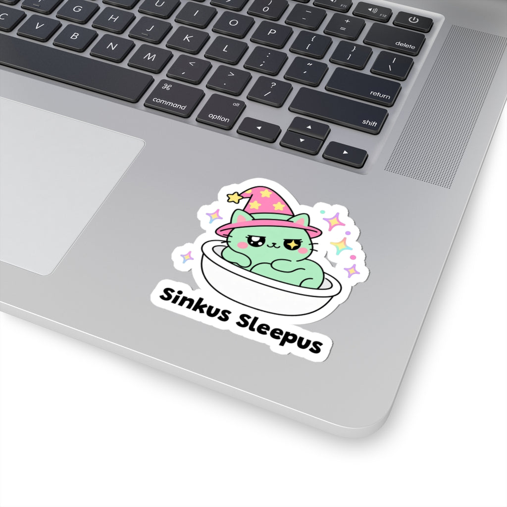 Sinkus Sleepus wizard cat sticker stuck on a silver laptop next to the keyboard
