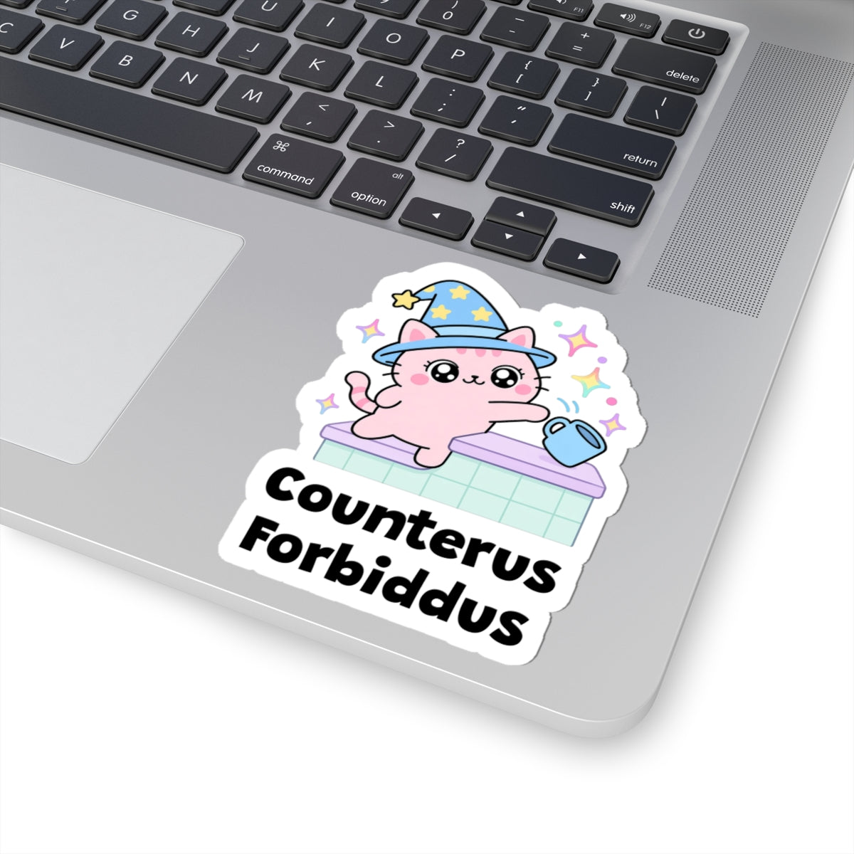 Counterus Forbiddus wizard cat sticker stuck on a silver laptop next to the keyboard