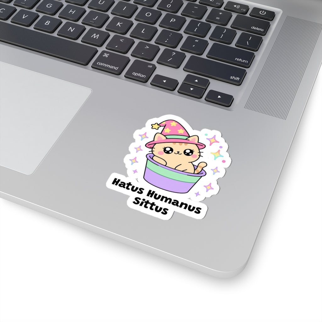 Hatus Humanus Sittus wizard cat sticker stuck on a silver laptop next to the keyboard