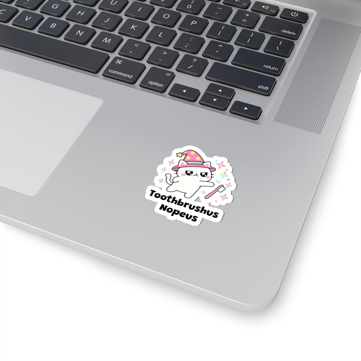 Toothbrushus Nopeus wizard cat sticker stuck on a silver laptop next to the keyboard