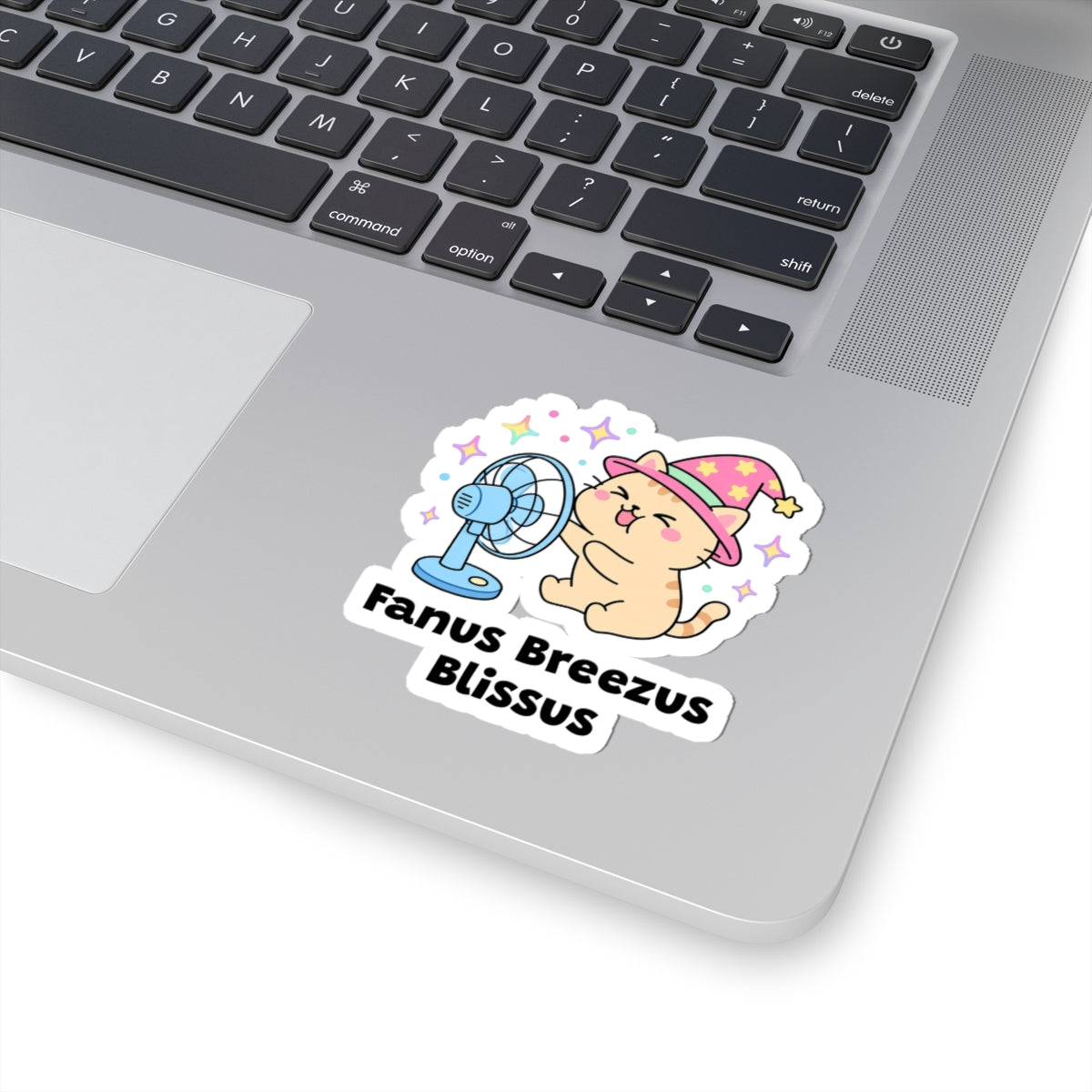 Fanus Breezus Blissus wizard cat sticker stuck on a silver laptop next to the keyboard