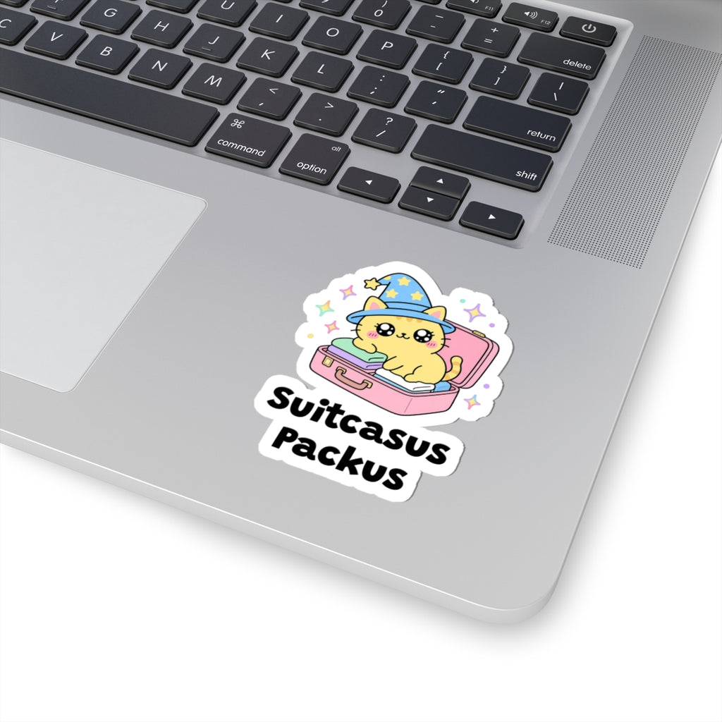 Suitcasus Packus wizard cat sticker stuck on a silver laptop next to the keyboard