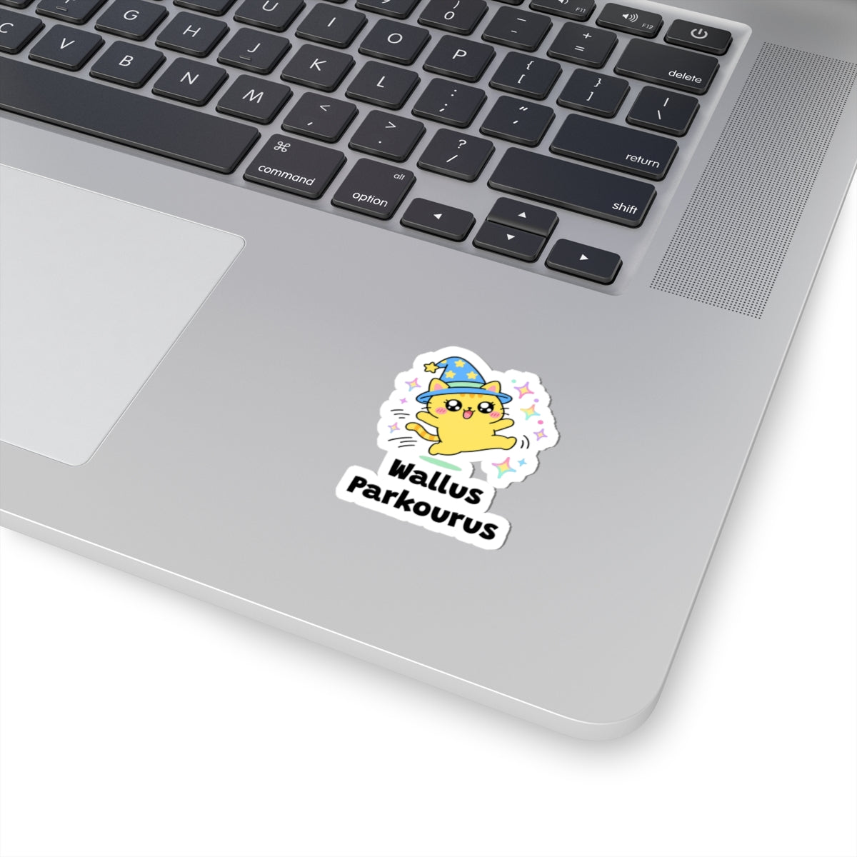 Wallus Parkourus wizard cat sticker stuck on a silver laptop next to the keyboard
