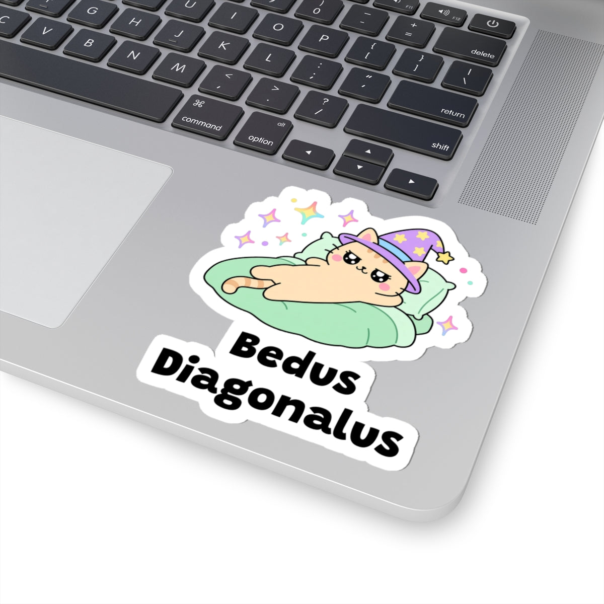 Bedus Diagonalus wizard cat sticker stuck on a silver laptop next to the keyboard