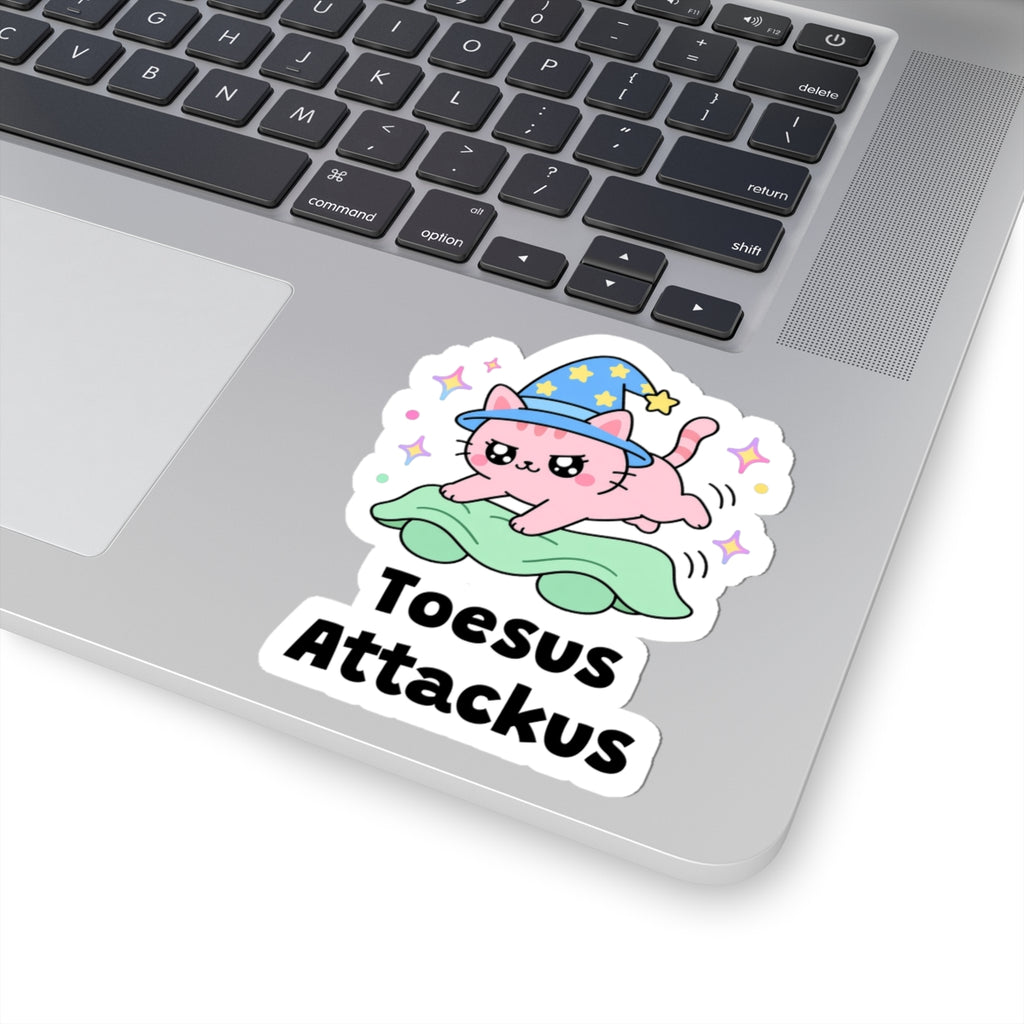 Toesus Attackus wizard cat sticker stuck on a silver laptop next to the keyboard