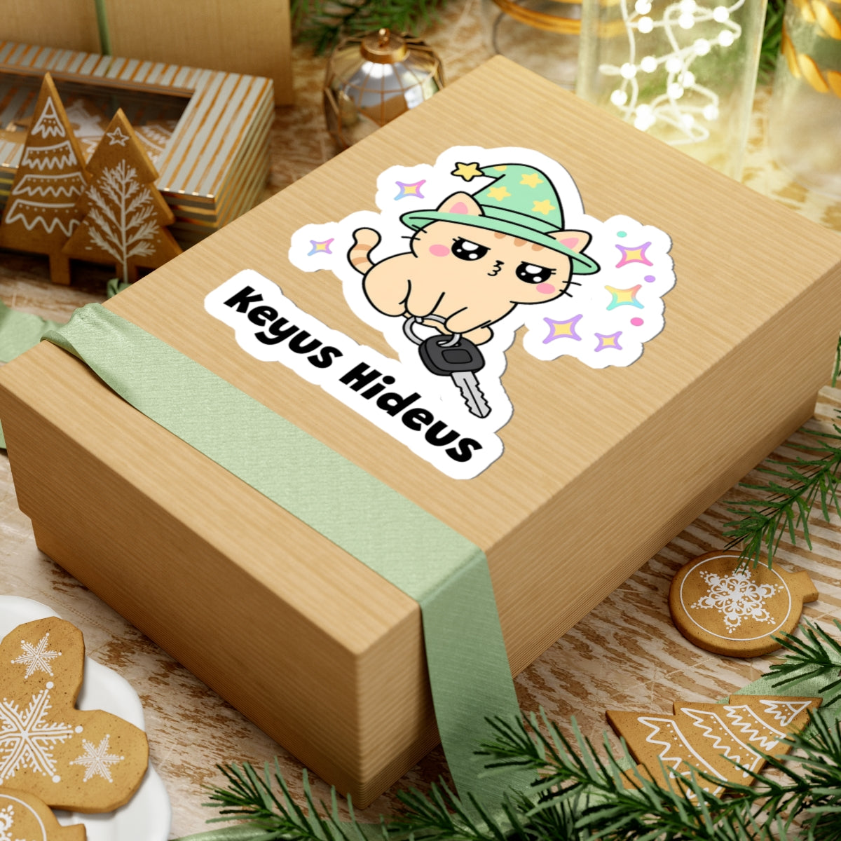 Keyus Hideus wizard cat sticker on a kraft gift box with a green ribbon and holiday cookies