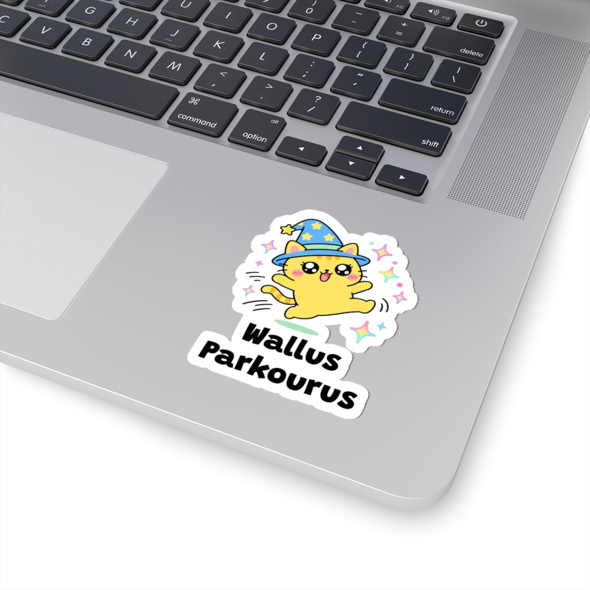 Wallus Parkourus wizard cat sticker stuck on a silver laptop next to the keyboard