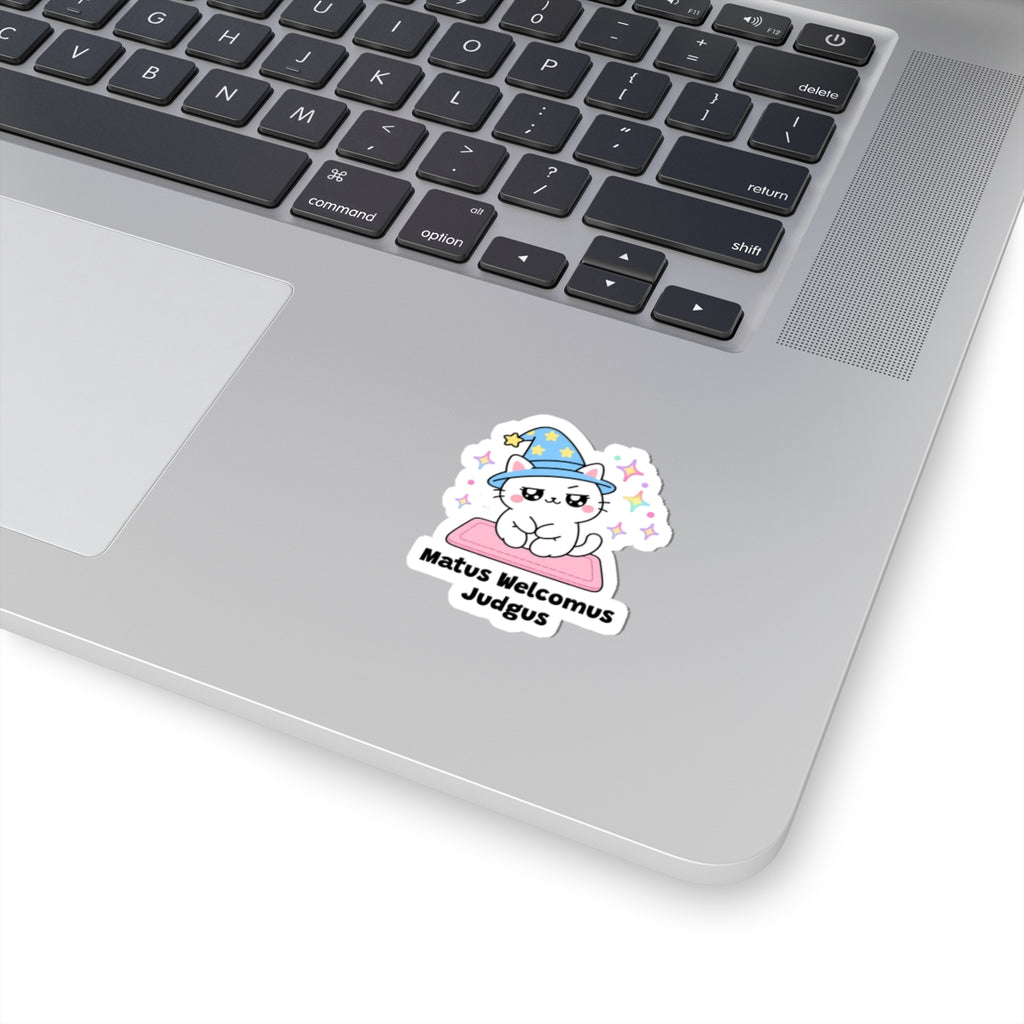 Matus Welcomus Judgus wizard cat sticker stuck on a silver laptop next to the keyboard