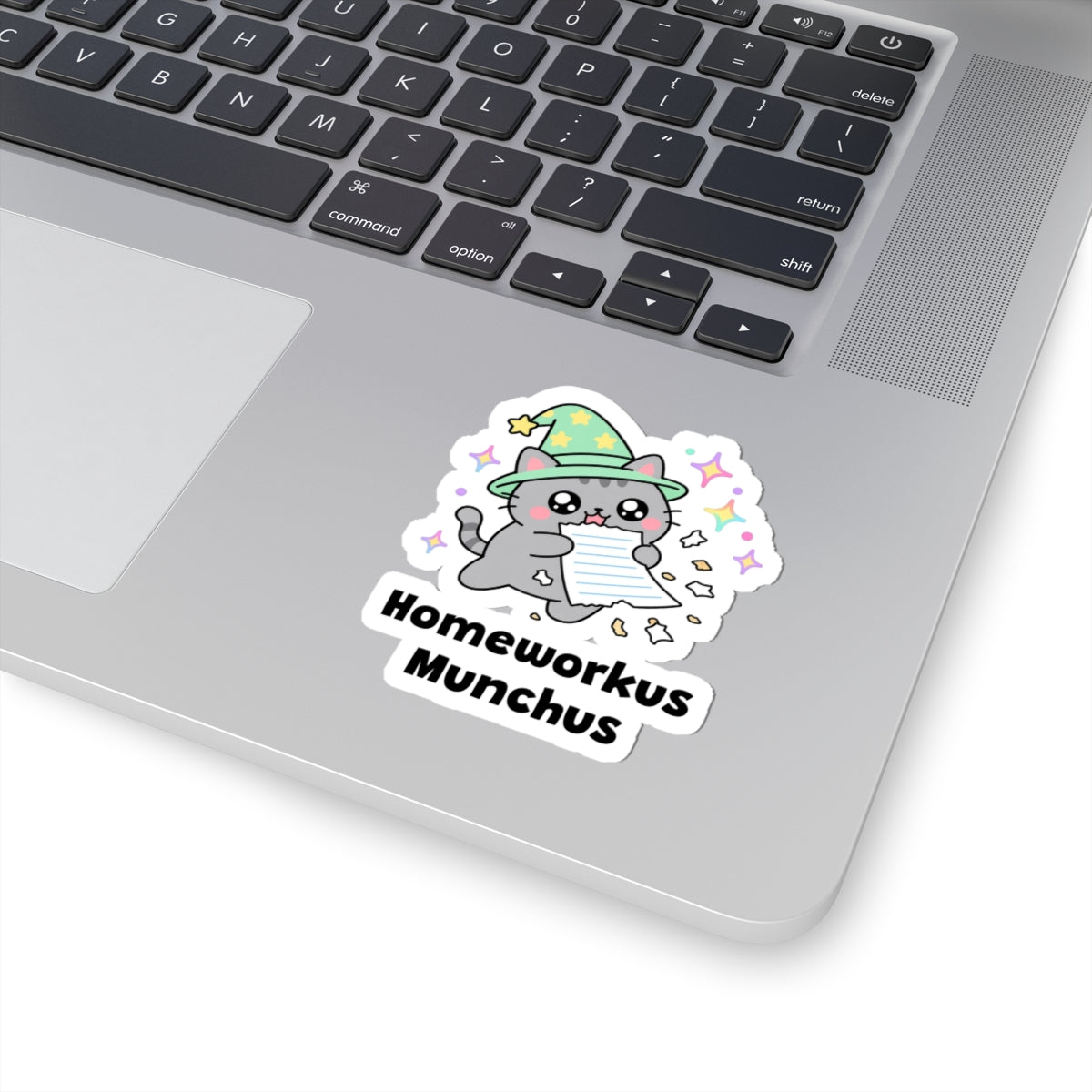 Homeworkus Munchus wizard cat sticker stuck on a silver laptop next to the keyboard