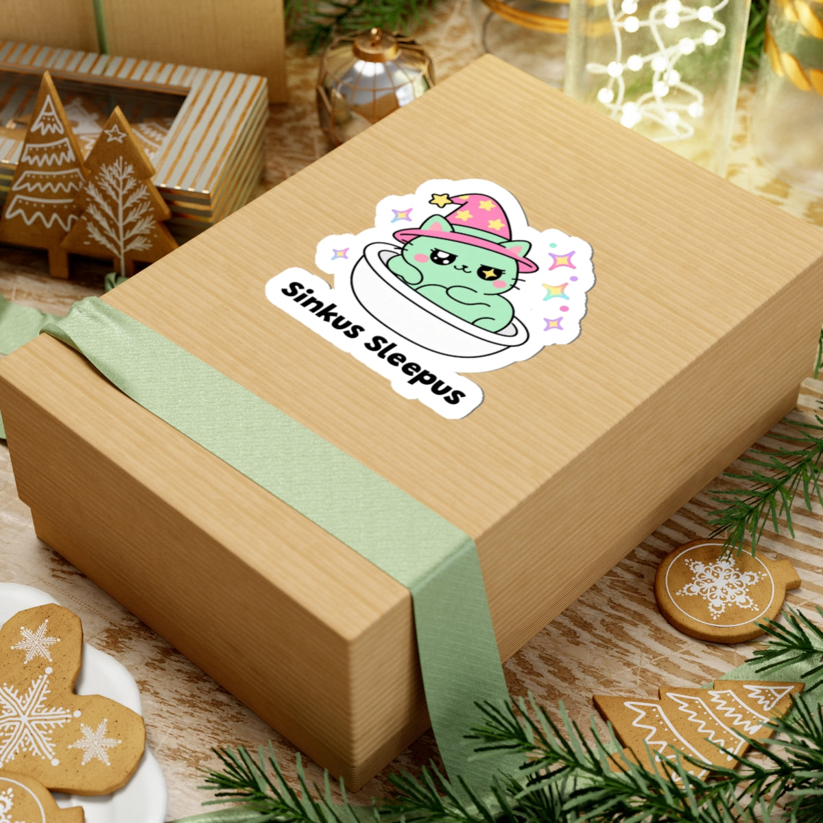 Sinkus Sleepus wizard cat sticker on a kraft gift box with a green ribbon and holiday cookies