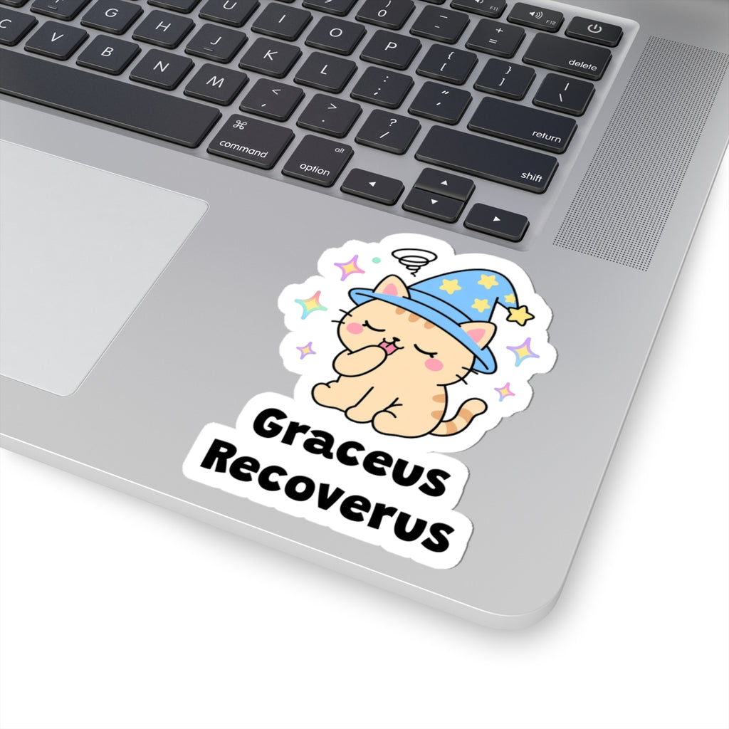Graceus Recoverus wizard cat sticker stuck on a silver laptop next to the keyboard