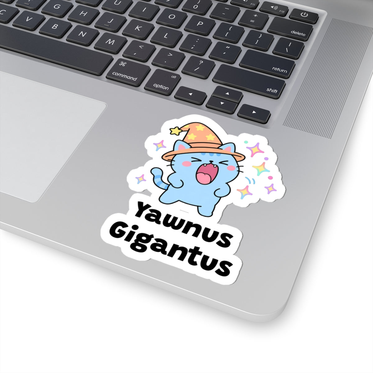 Yawnus Gigantus wizard cat sticker stuck on a silver laptop next to the keyboard