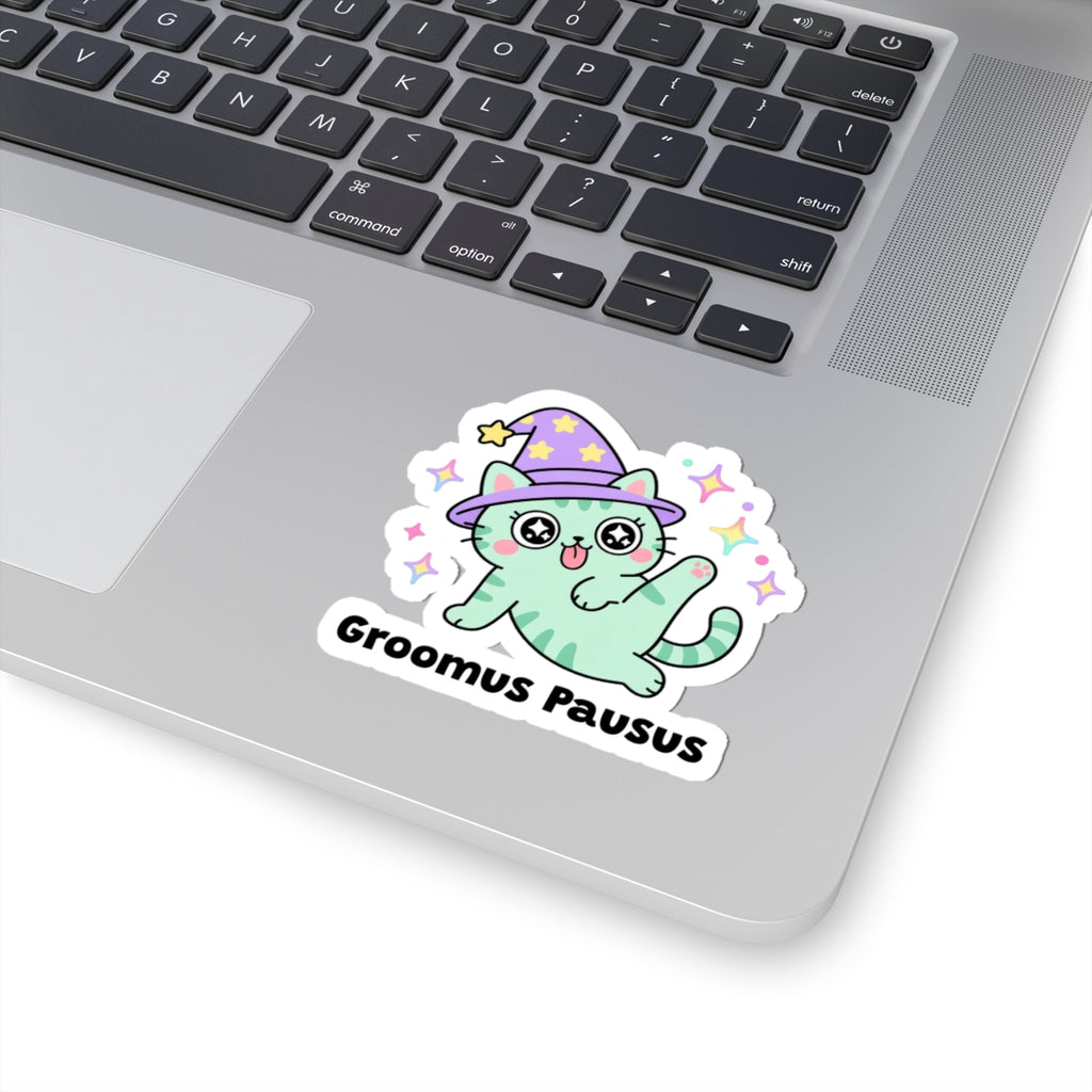 Groomus Pausus wizard cat sticker stuck on a silver laptop next to the keyboard
