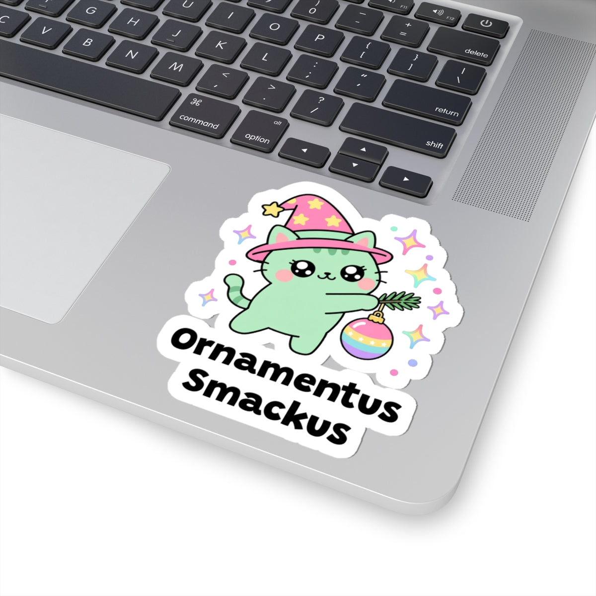Ornamentus Smackus wizard cat sticker stuck on a silver laptop next to the keyboard