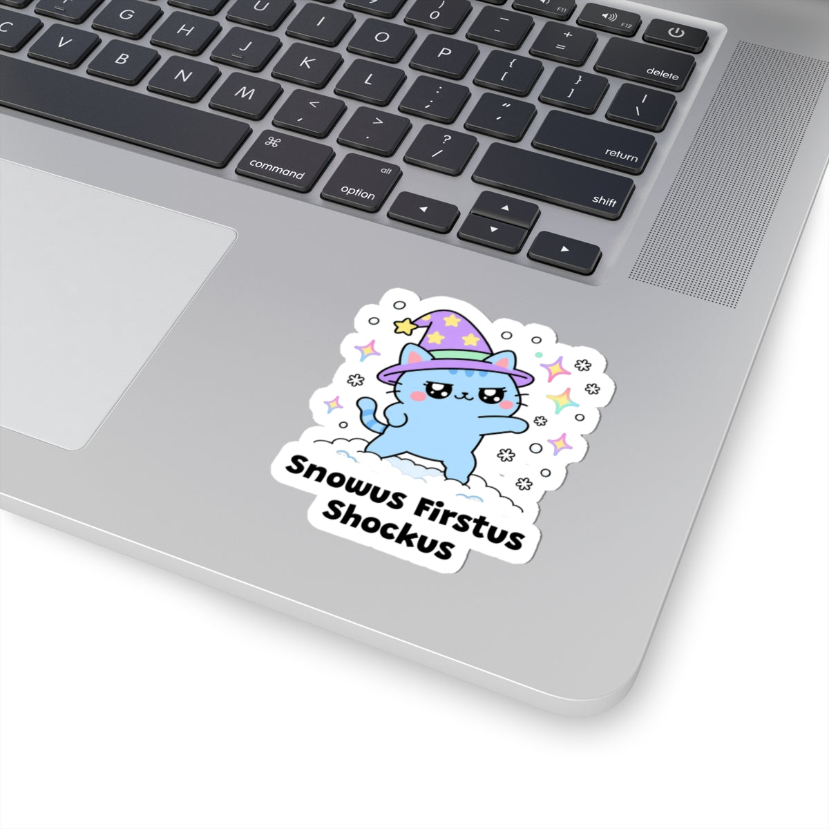 Snowus Firstus Shockus wizard cat sticker stuck on a silver laptop next to the keyboard