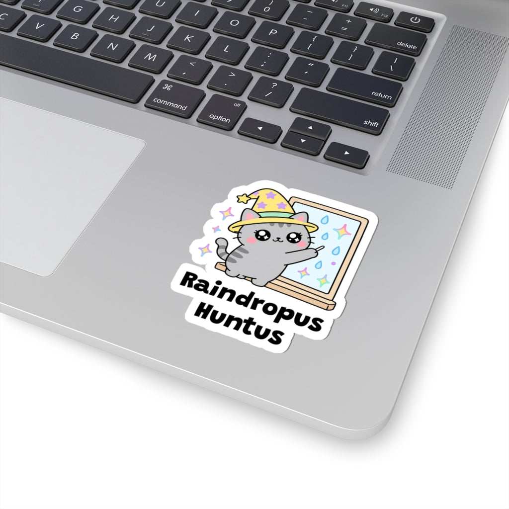 Raindropus Huntus wizard cat sticker stuck on a silver laptop next to the keyboard
