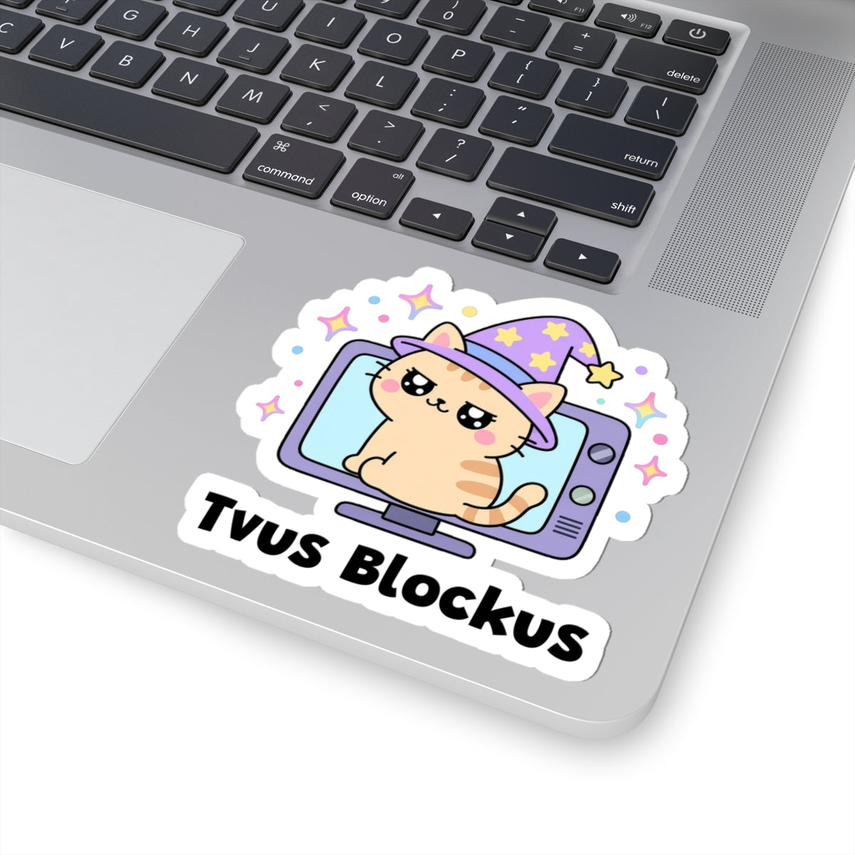 Tvus Blockus wizard cat sticker stuck on a silver laptop next to the keyboard
