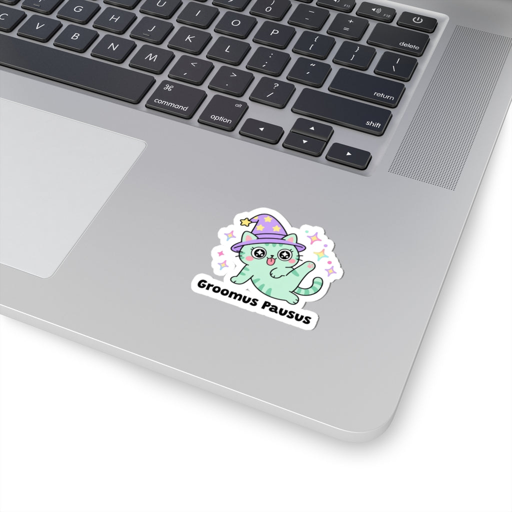 Groomus Pausus wizard cat sticker stuck on a silver laptop next to the keyboard