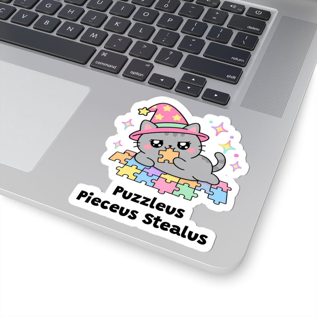 Puzzleus Pieceus Stealus wizard cat sticker stuck on a silver laptop next to the keyboard