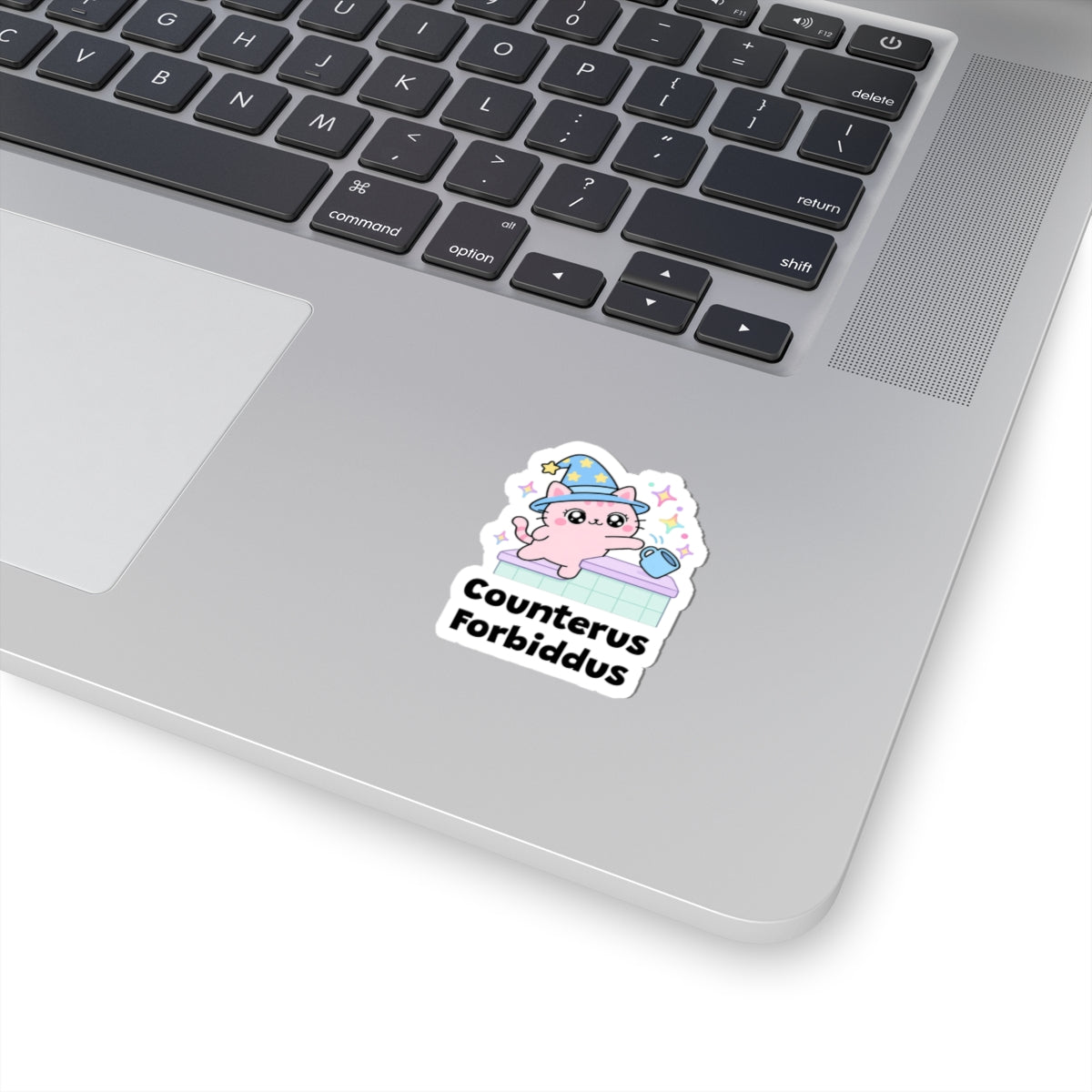 Counterus Forbiddus wizard cat sticker stuck on a silver laptop next to the keyboard