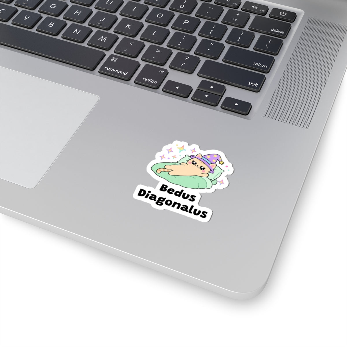 Bedus Diagonalus wizard cat sticker stuck on a silver laptop next to the keyboard